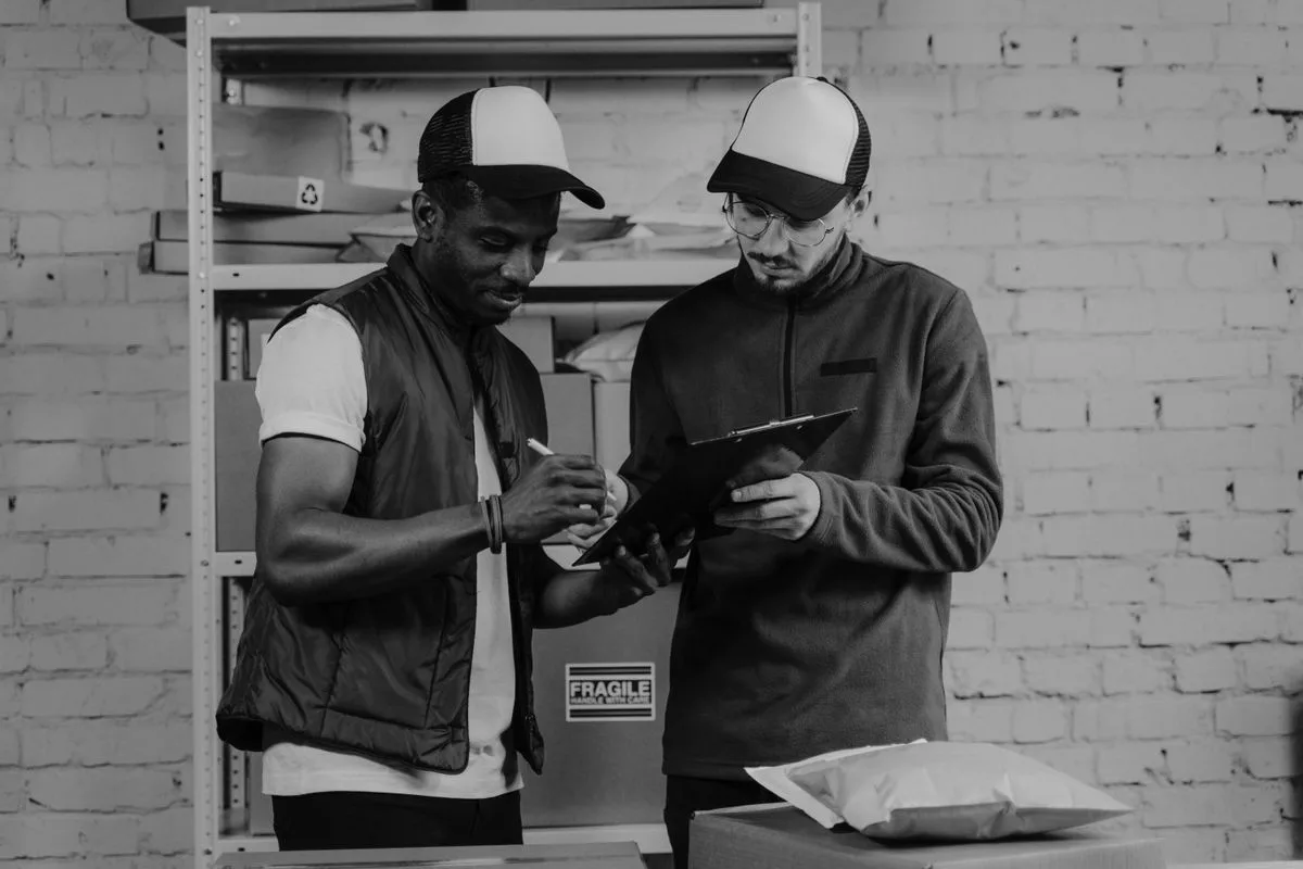 Warehouse workers checking package details with a clipboard